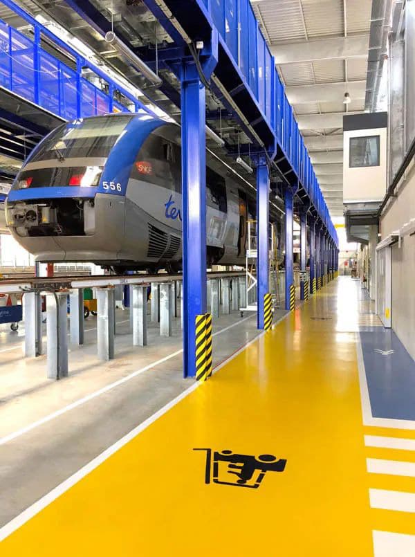 Sol résine jaune avec marquage de sécurité dans un atelier de maintenance ferroviaire SNCF